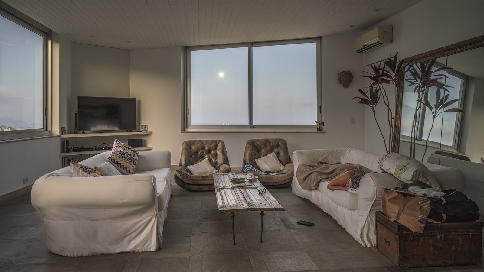 Bright living room with wide windows overlooking the water at dusk