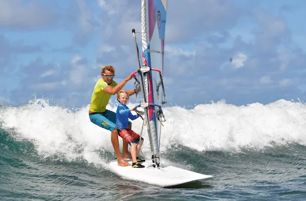 Teenagers practicing windsurfing together on calm coastal waters